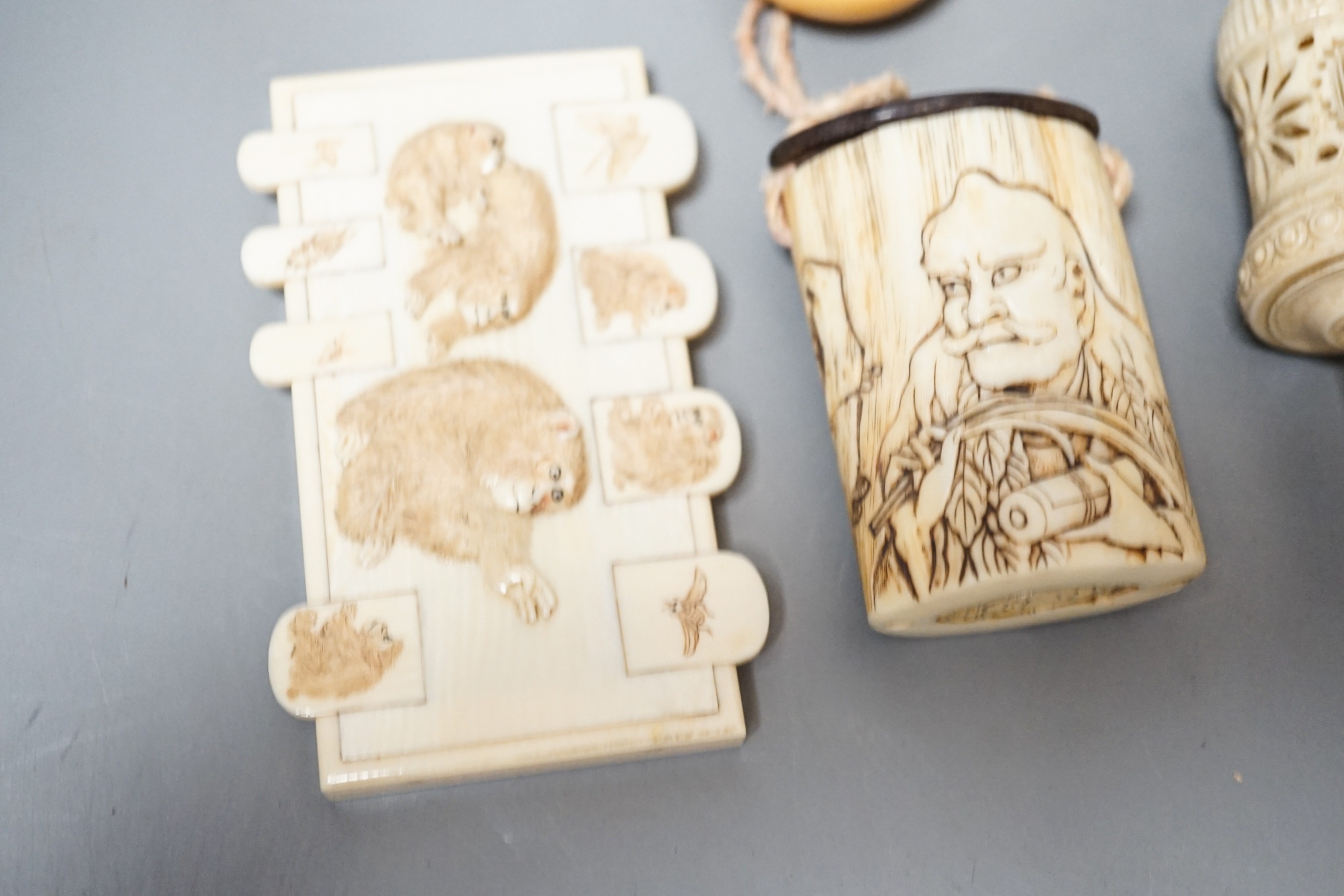 Three Japanese Ivory figures of men, a similar bezique marker, a Japanese staghorn single section inro with ivory manju, a Chinese ivory carving and a bone needlework container